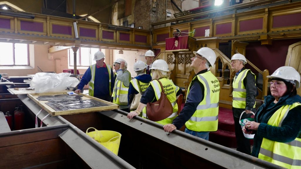 Visitors in yellow hi-viz look at samples of restored stained glass