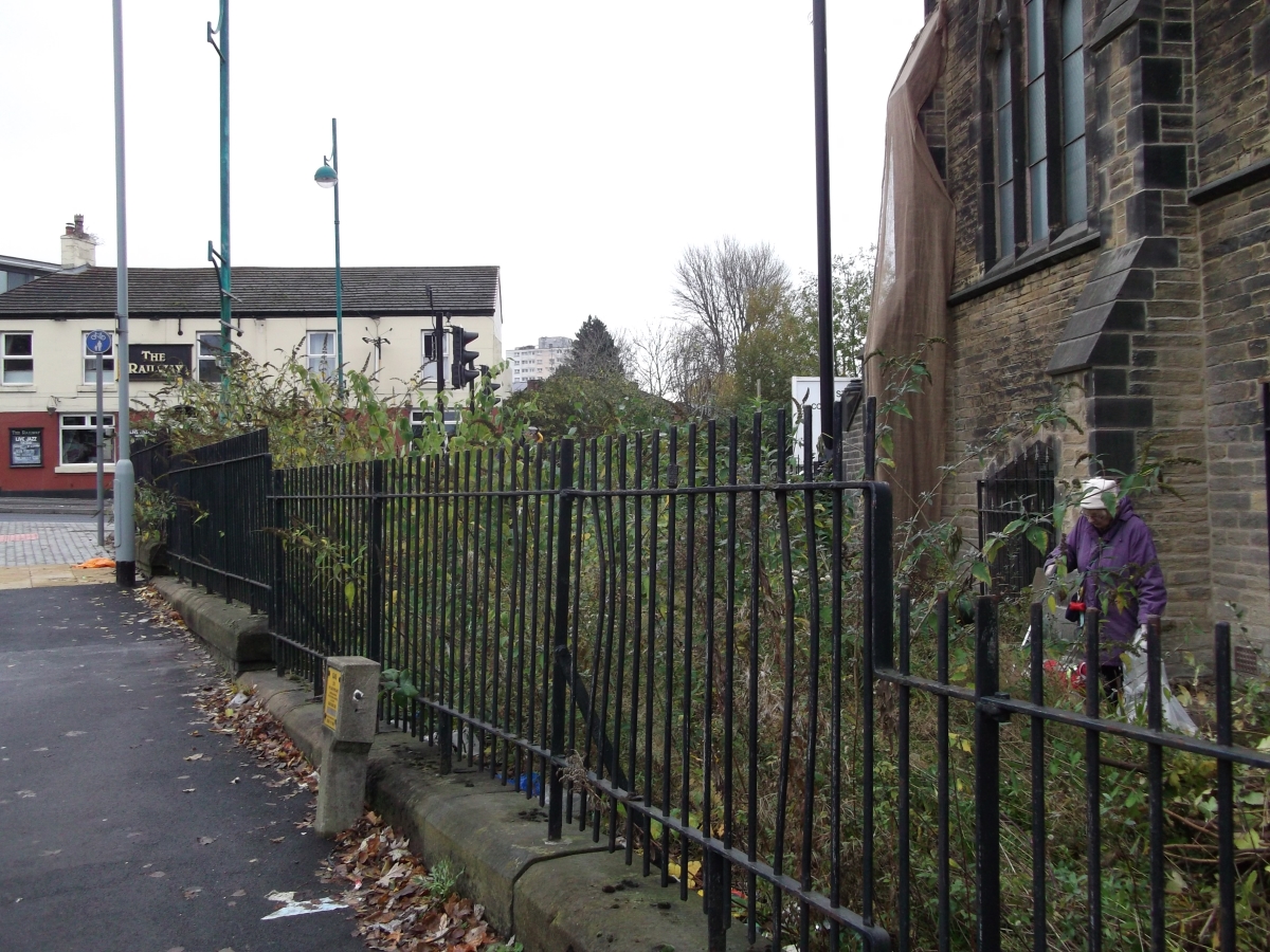 A volunteer works to clear away overgrown plants at the side of the church