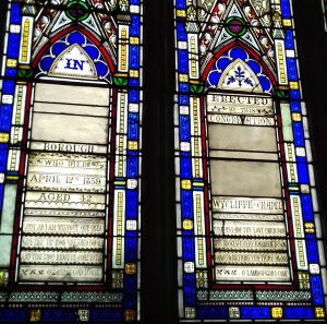 Two panels in the stained glass window with verses from Just as I am and John Hampson's date of death