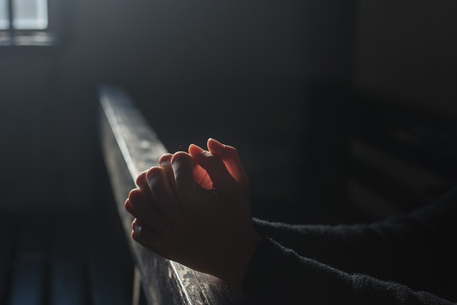 Hands clasped in prayer at an altar rail