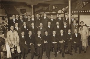 Four rows of men, all bar one of whom is in normal attire for 1924