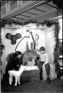 Full sized nativity scene with grotto , large furry donkey and realistic plastic lamb. A lady and boy interact with the display.