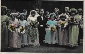 Old colourised picture of children dressed as Bride, groom, bridesmaids and guests