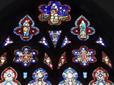 Stained glass in the arched top section depicting Charity, Faith and Hope