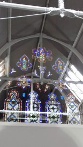 Stained glass window reflected in interior window with beams visible inside